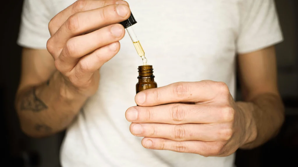 (A person measuring CBD oil with a dropper)