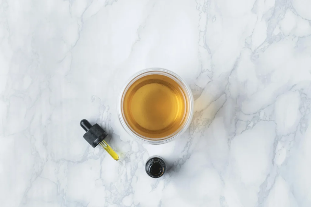 Glass dropper with CBD oil reflecting natural light